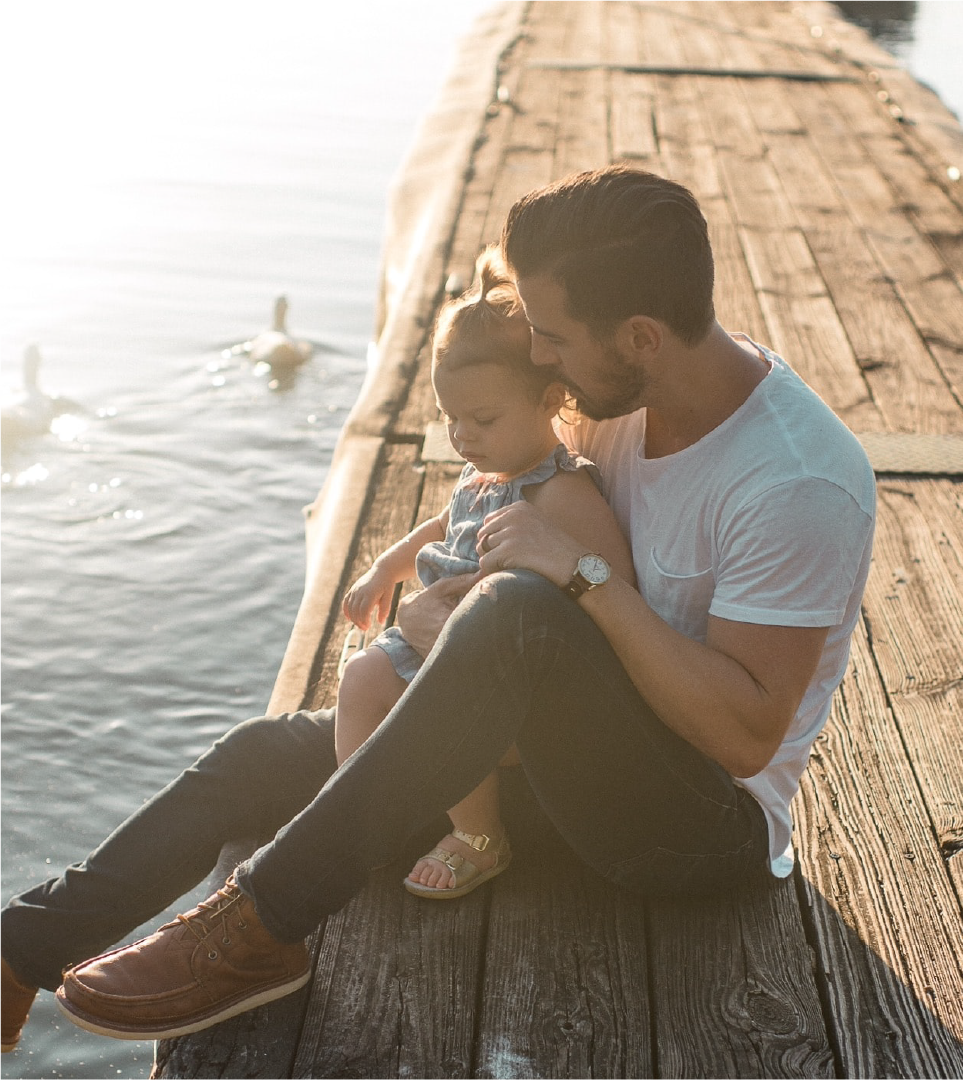 View of a father and daughter sitting on a dock